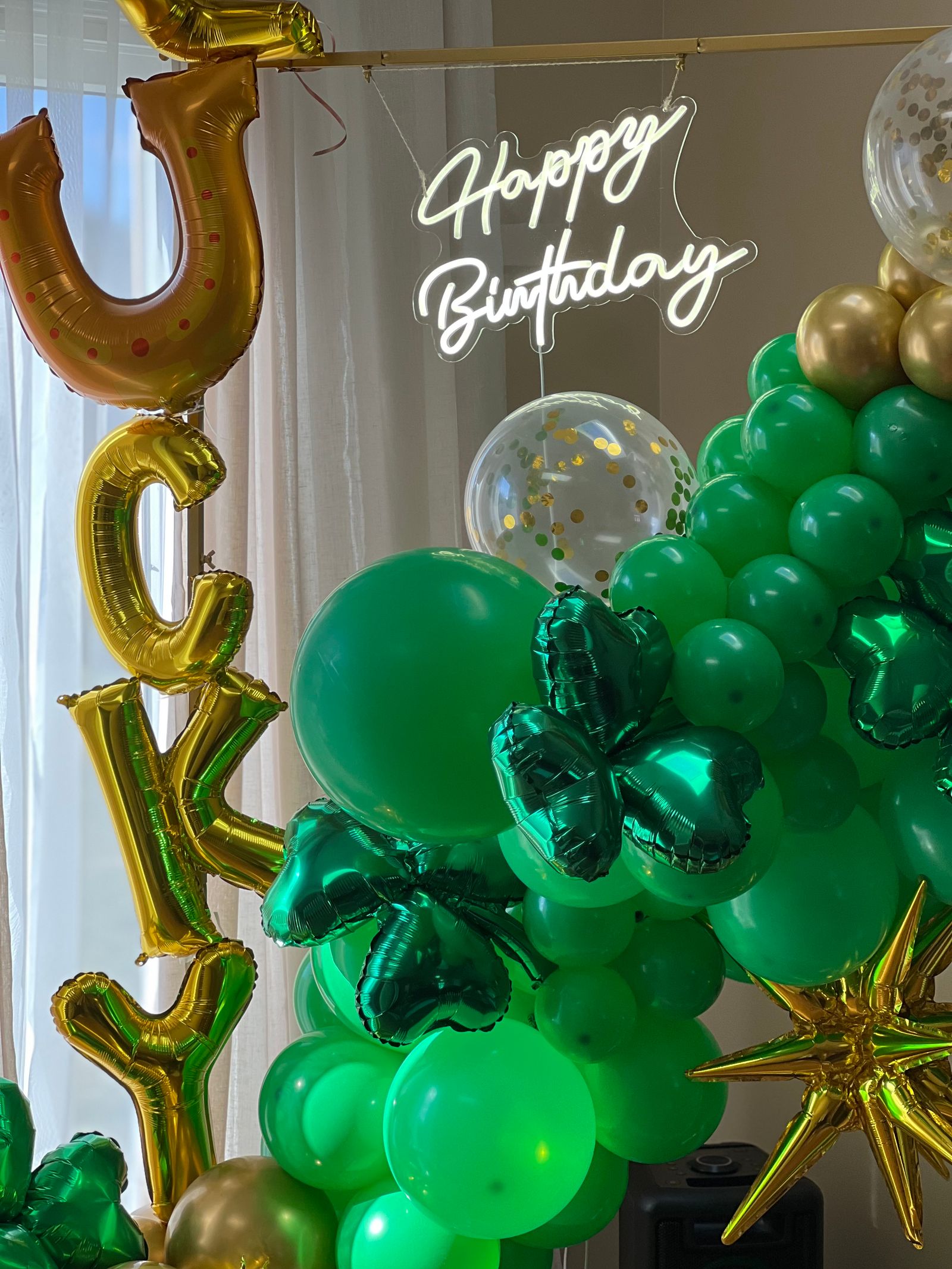 Green and gold birthday balloons and a happy birthday sign