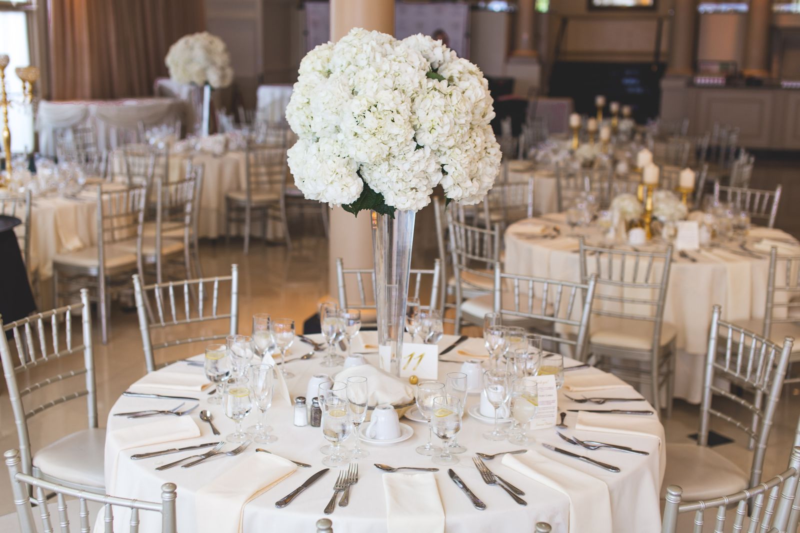 Reception tables with tall floral arrangements and white linens
